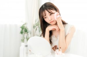 メイク中に落ち込む,悩む女性（肌荒れ）