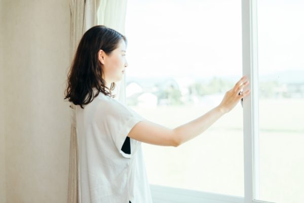 窓から外を眺める女性